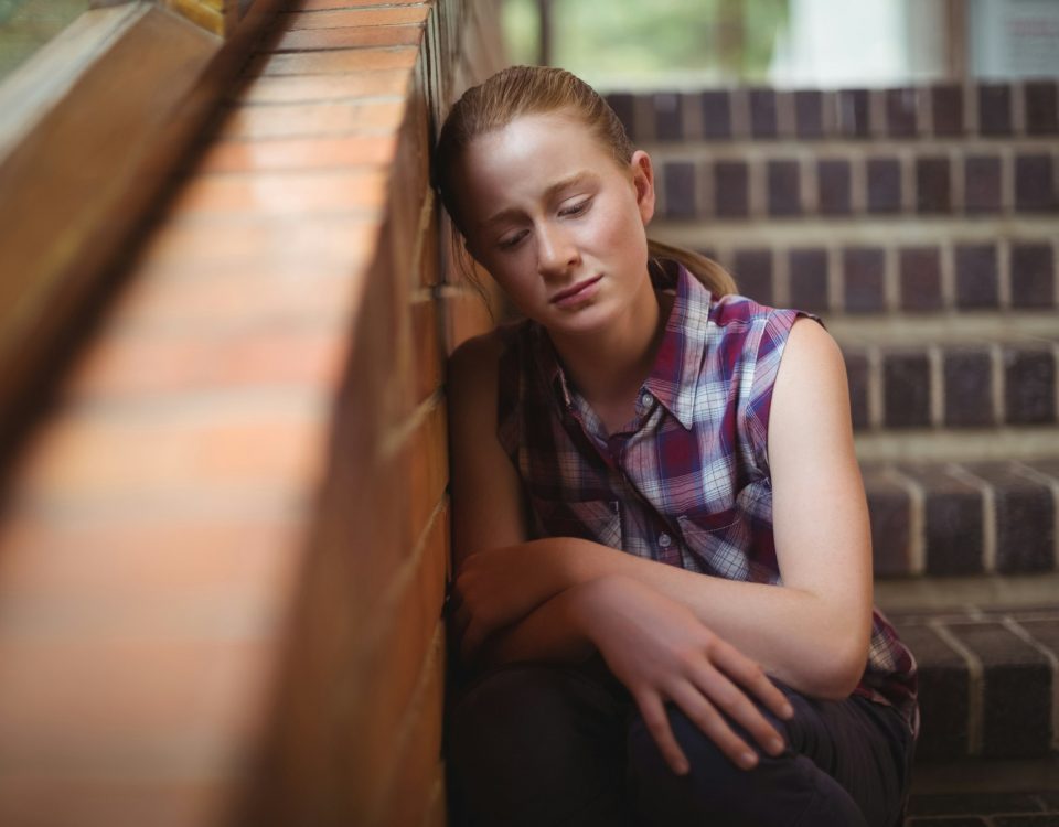 Sad schoolgirl sitting alone on staircase