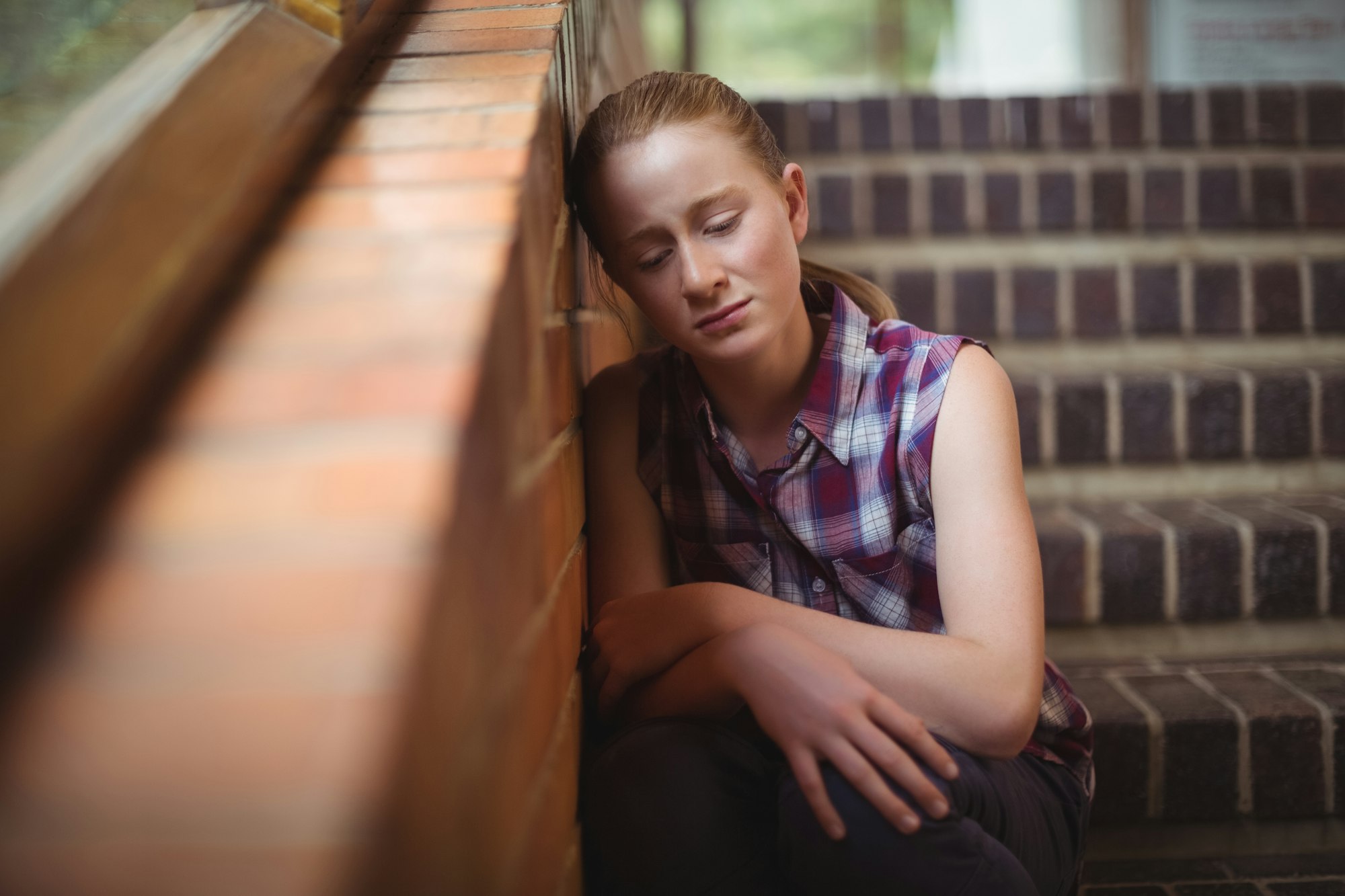 Sad schoolgirl sitting alone on staircase