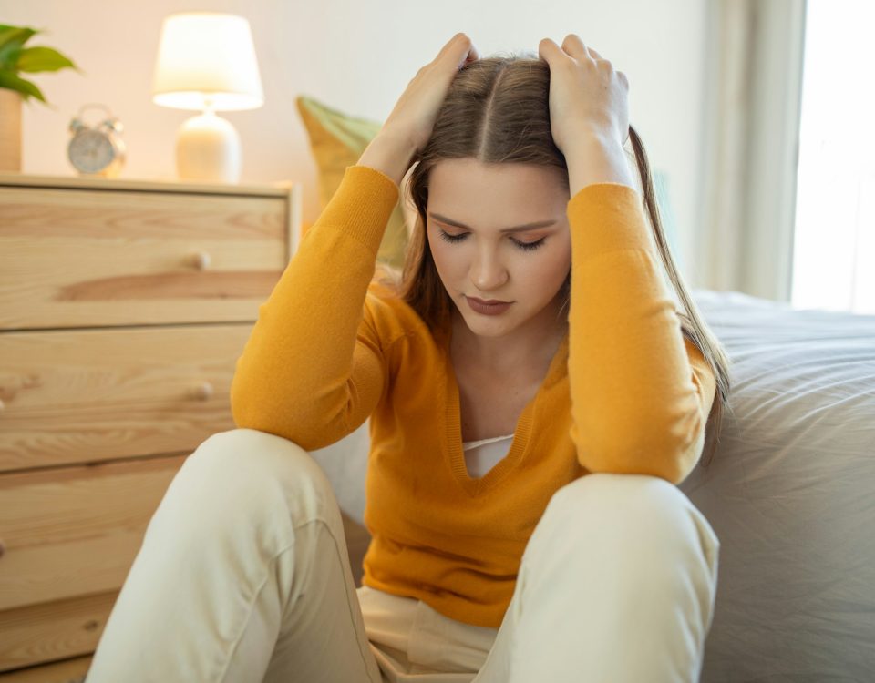 Teen Girl Sitting on Bedroom Floor Appearing Upset in Daylight