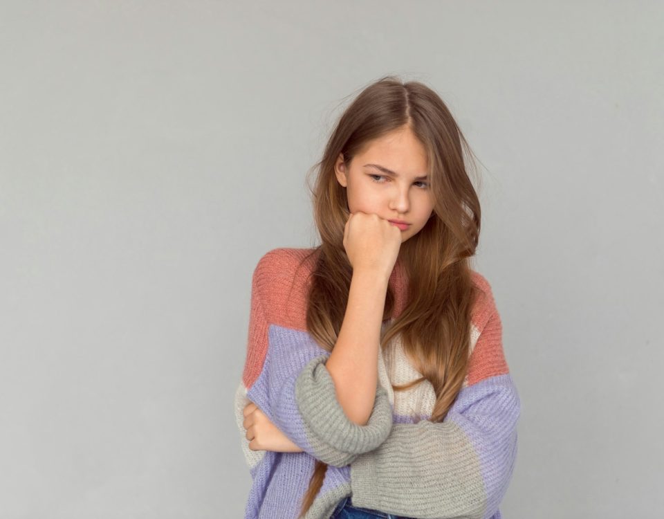 Teenage girl crying, actress posing on grey background, emotional portrait of grudge