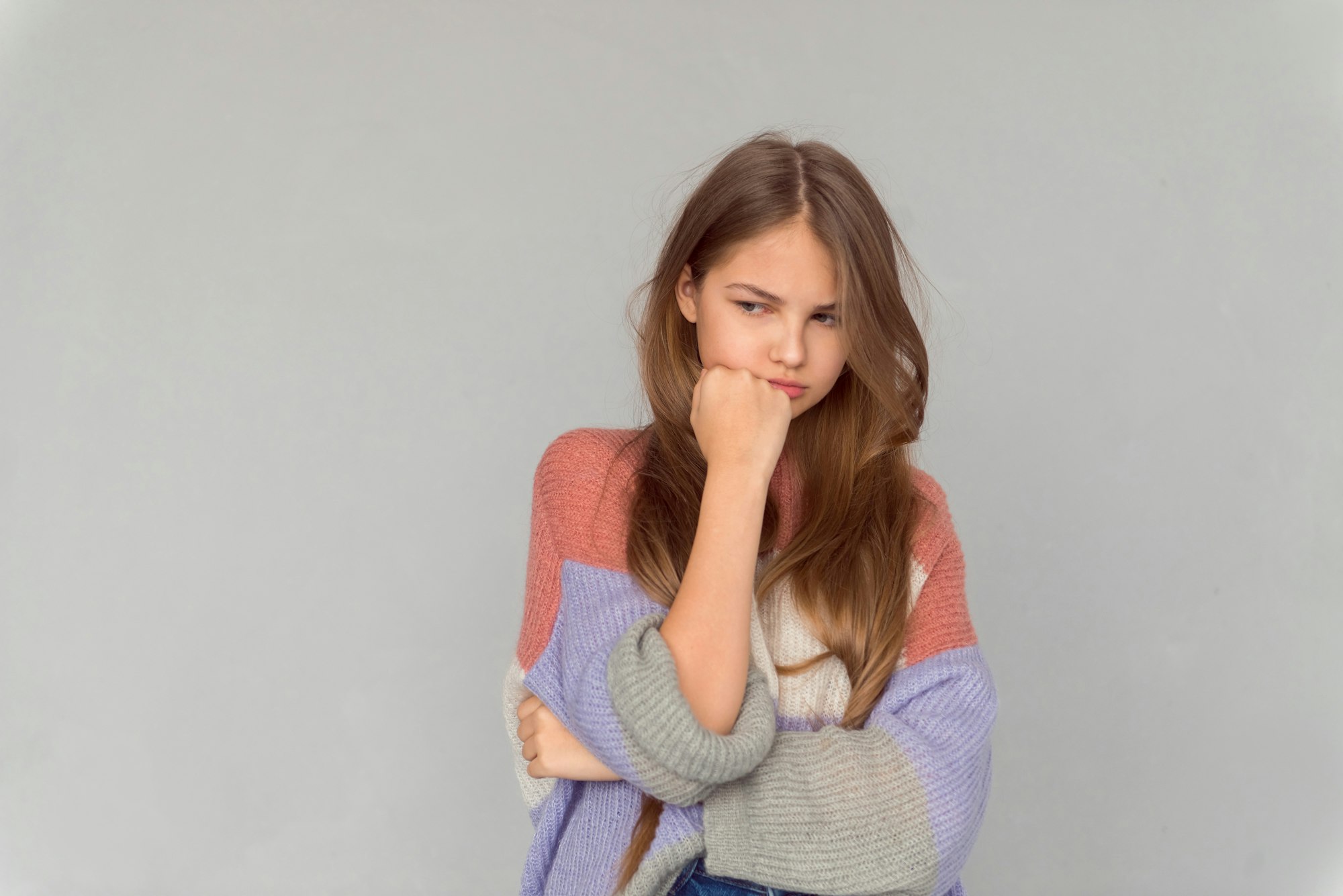 Teenage girl crying, actress posing on grey background, emotional portrait of grudge