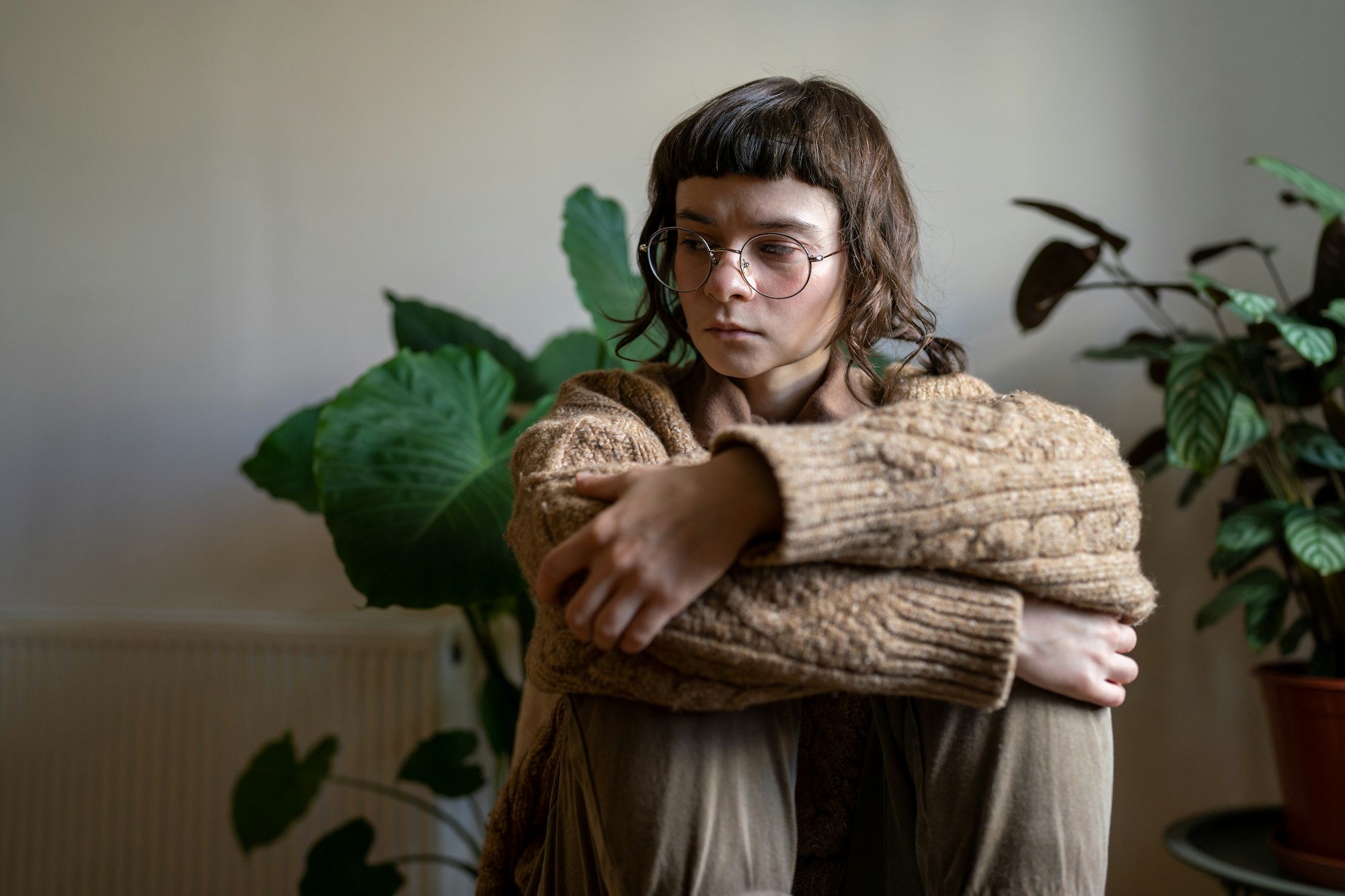 Thoughtful hopeless sad teen girl in crisis, depression, stress, sorrow sitting alone at home