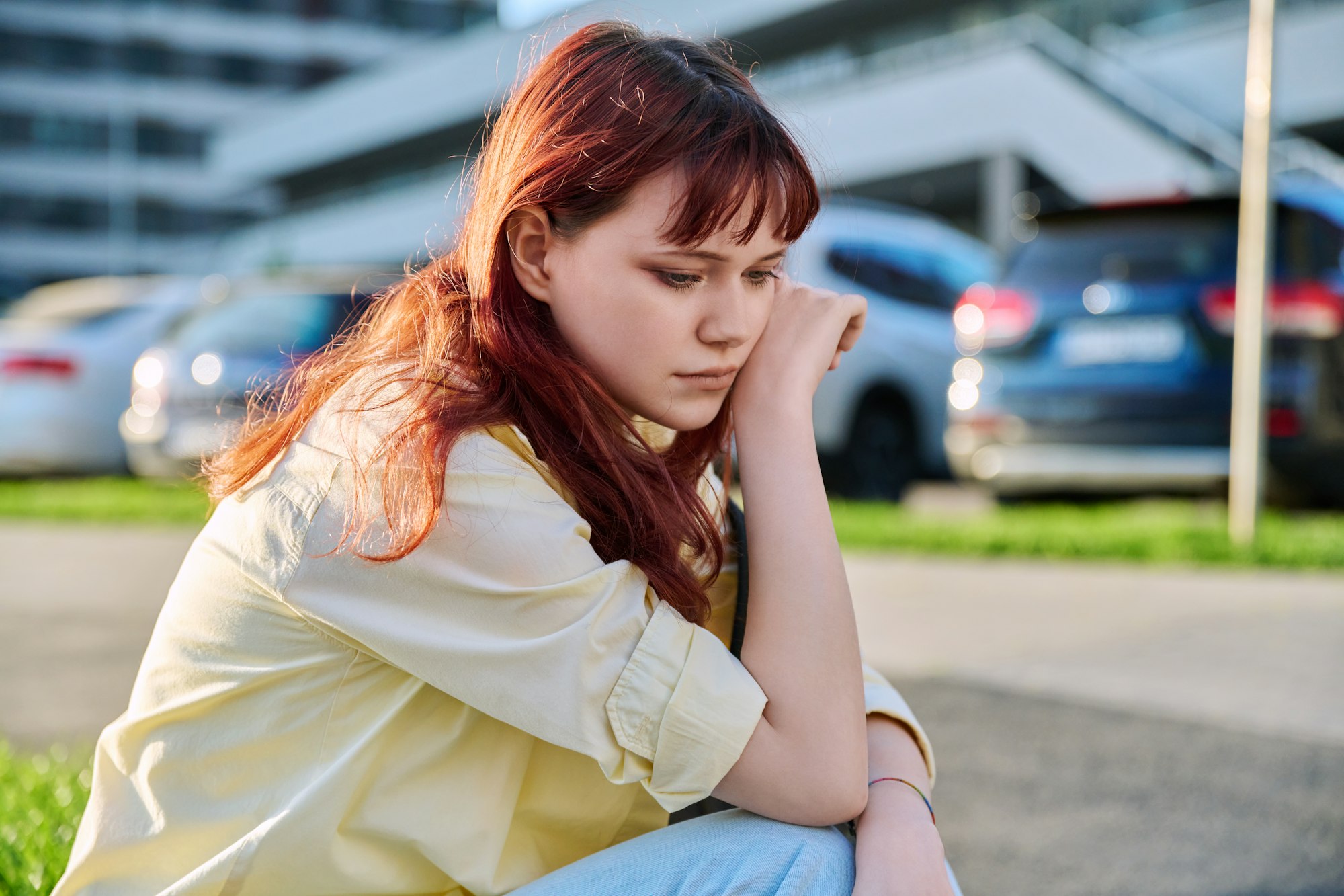 Upset sad unhappy young female sitting outdoor on steps