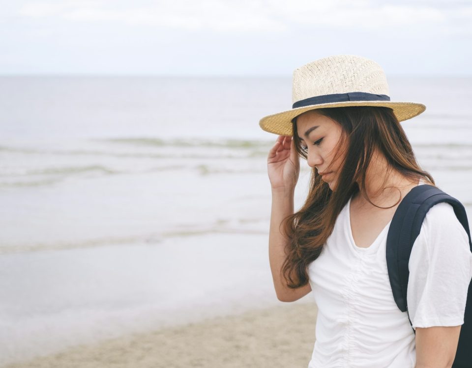 A sad woman standing alone by the sea