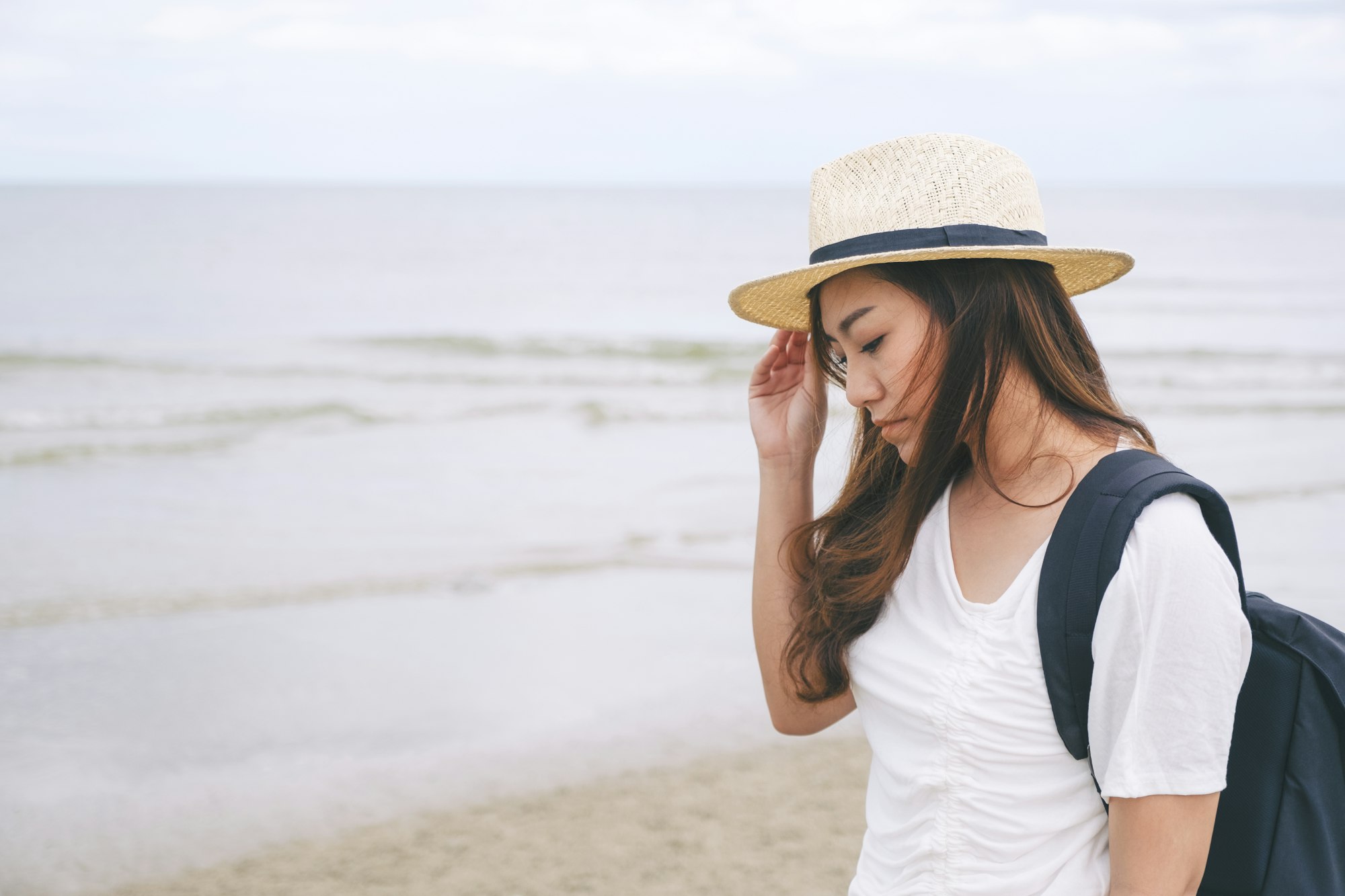 A sad woman standing alone by the sea