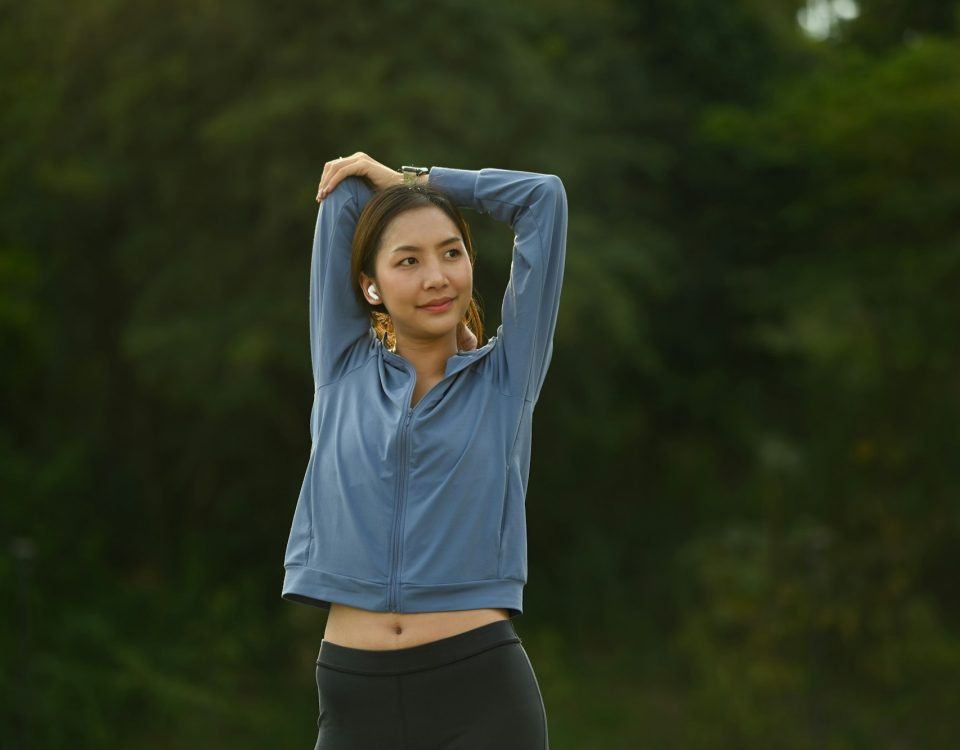 Image of sporty asian woman in sportswear stretching her arms, warming up his body.