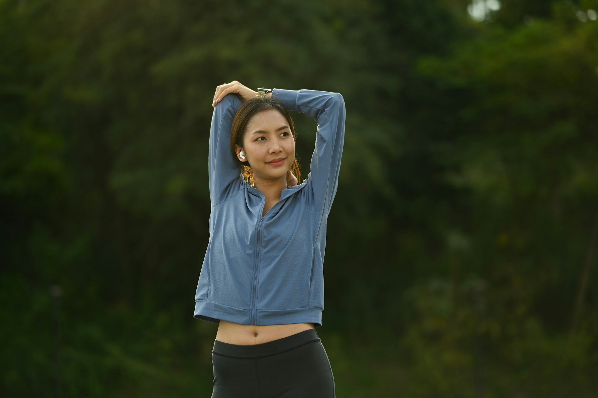 Image of sporty asian woman in sportswear stretching her arms, warming up his body.