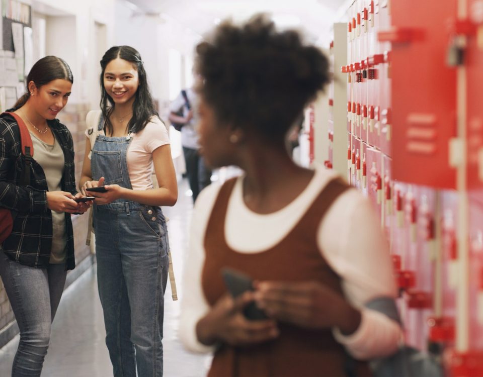 Shot of a teenage girl using a smartphone next to her locker and being bullied at high school