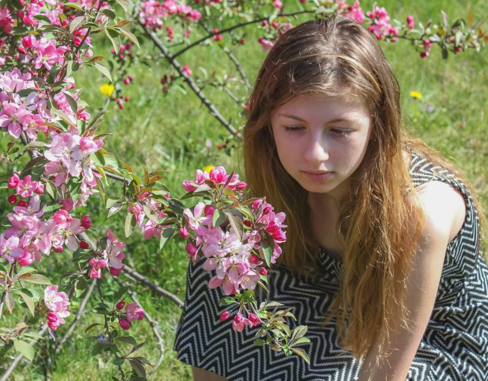 Young teen girl solemnly looking at and smelling flowers to uplift her mood and feelings of sadness