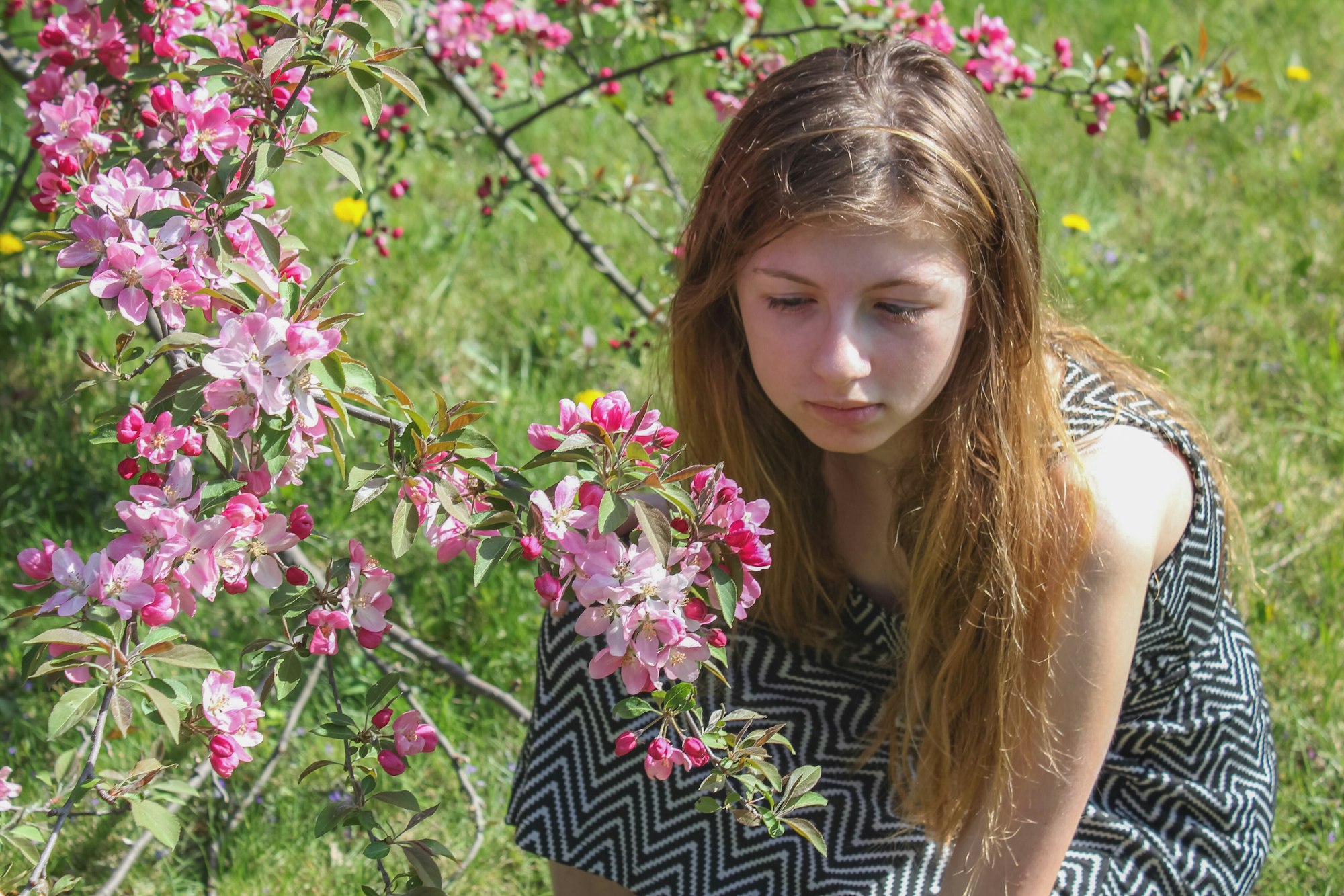 Young teen girl solemnly looking at and smelling flowers to uplift her mood and feelings of sadness