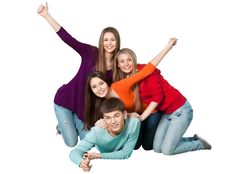 Four teens happily posing for a picture on the floor with their arms in the air.