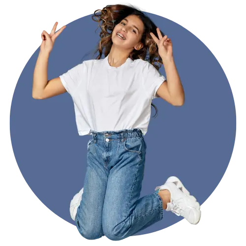 Teen girl jumping in the air while holding her hands in a peace symbol.