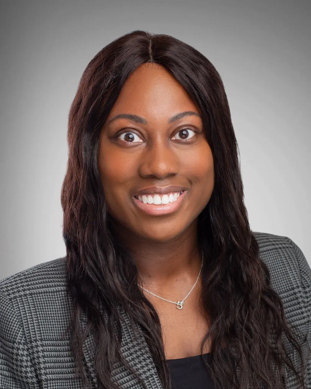 Woman in a dark suit smiling with dark hair.