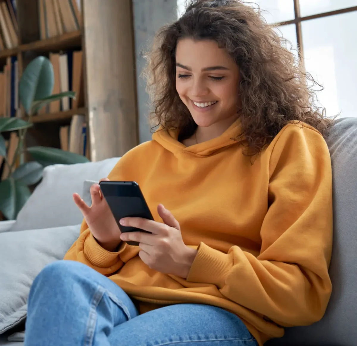 Smiling young woman seated and looking at her phone.