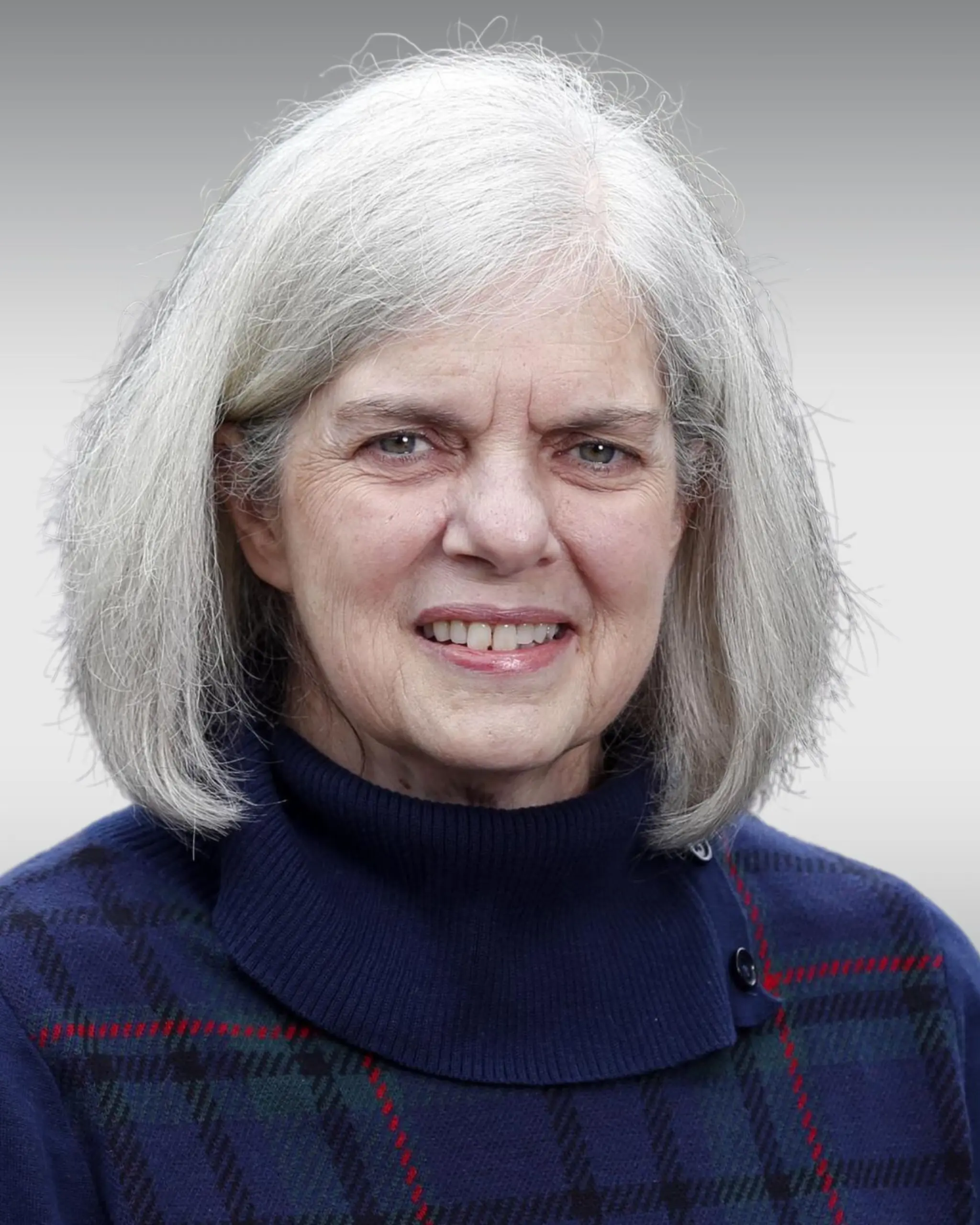 Woman in dark clothes smiling with gray hair.