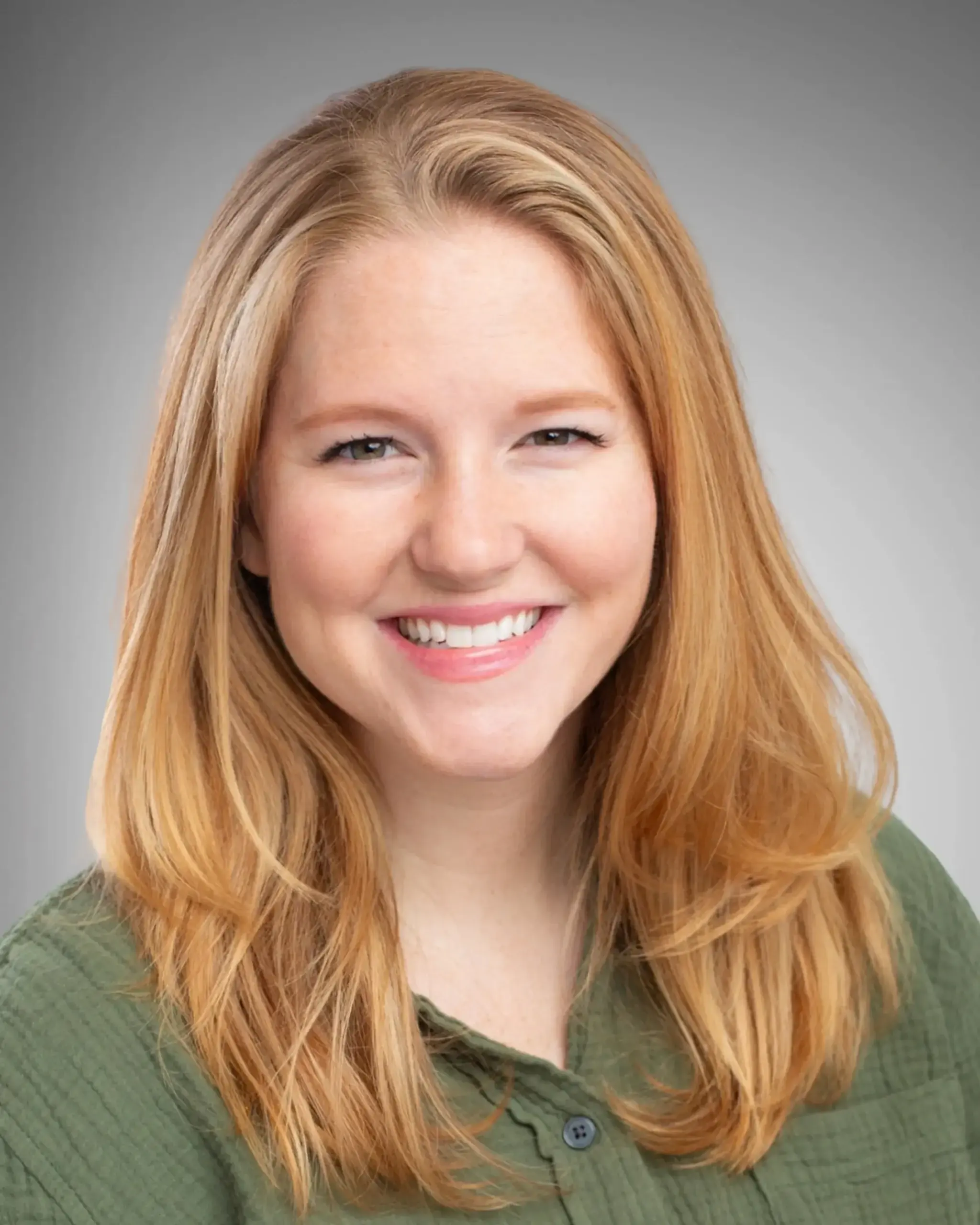 Smiling woman in a green shirt with light hair.