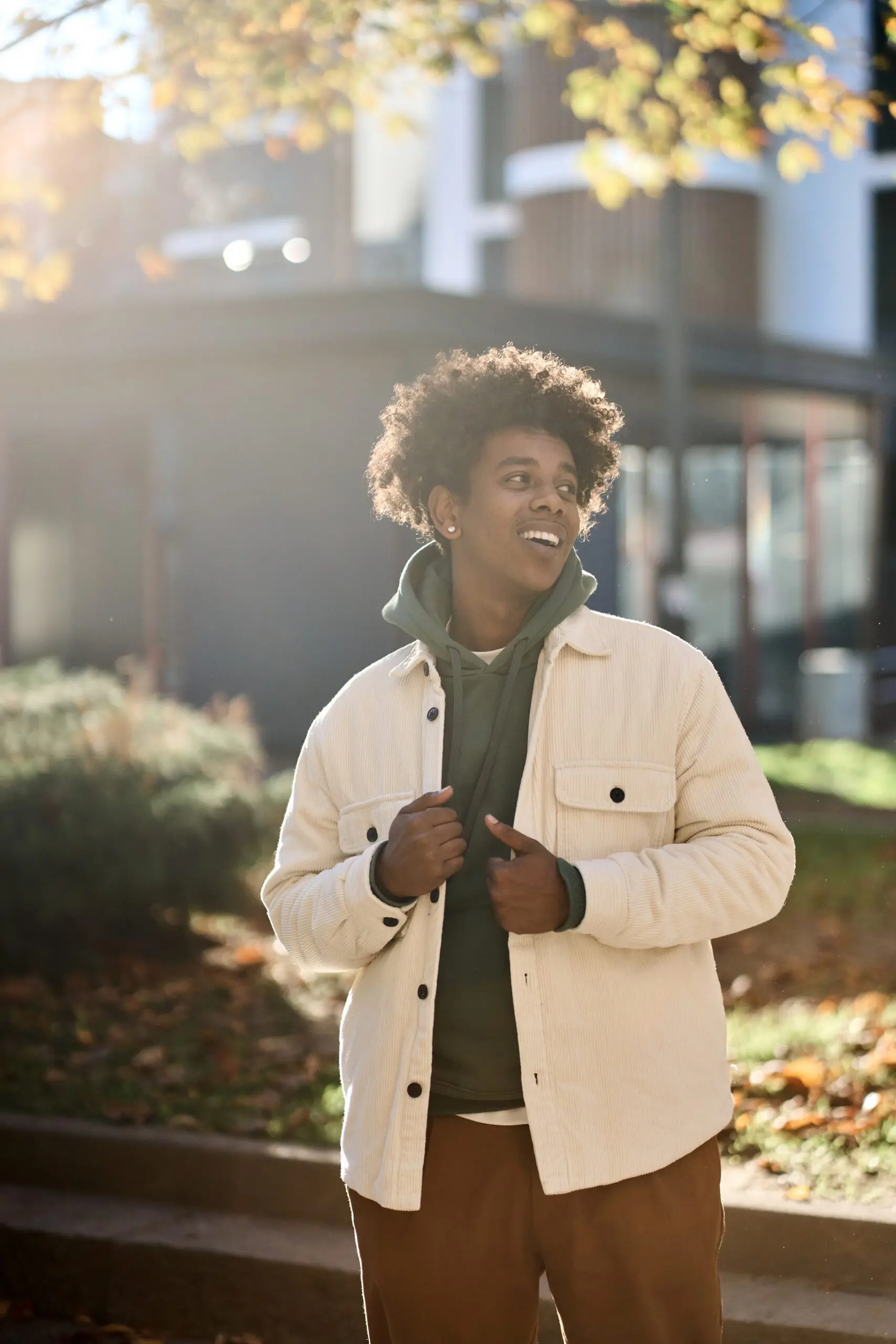 Young man outside, smiling and looking over his shoulder.