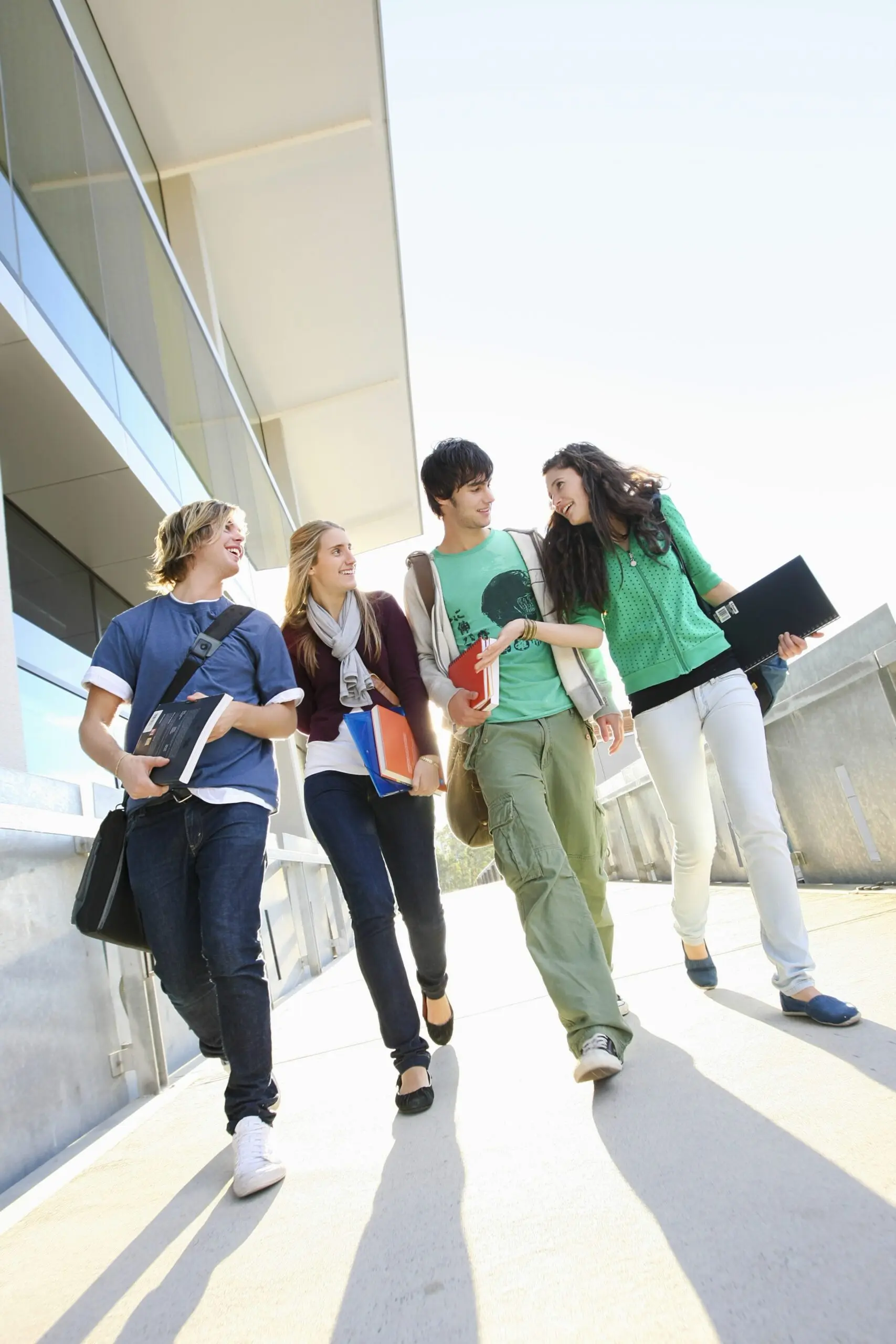 Group of four teens walking with books and book bags.