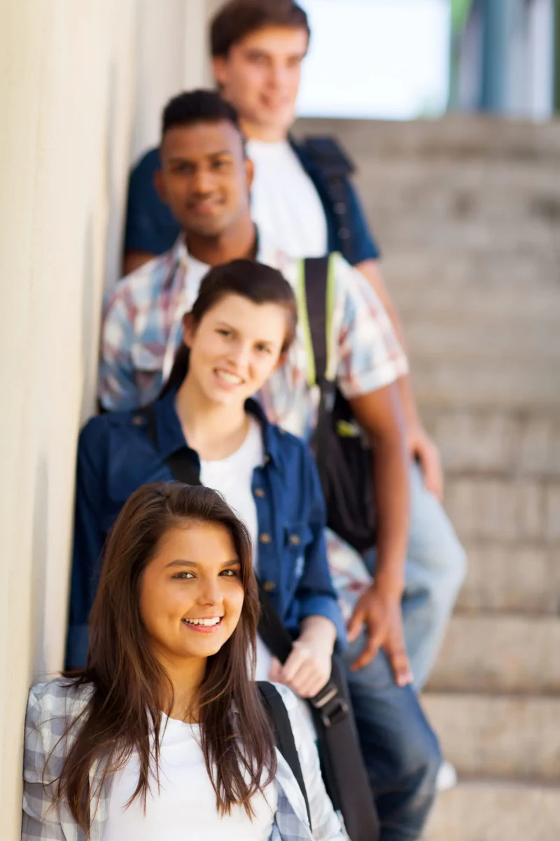 Four young people smiling in a group on stairs.