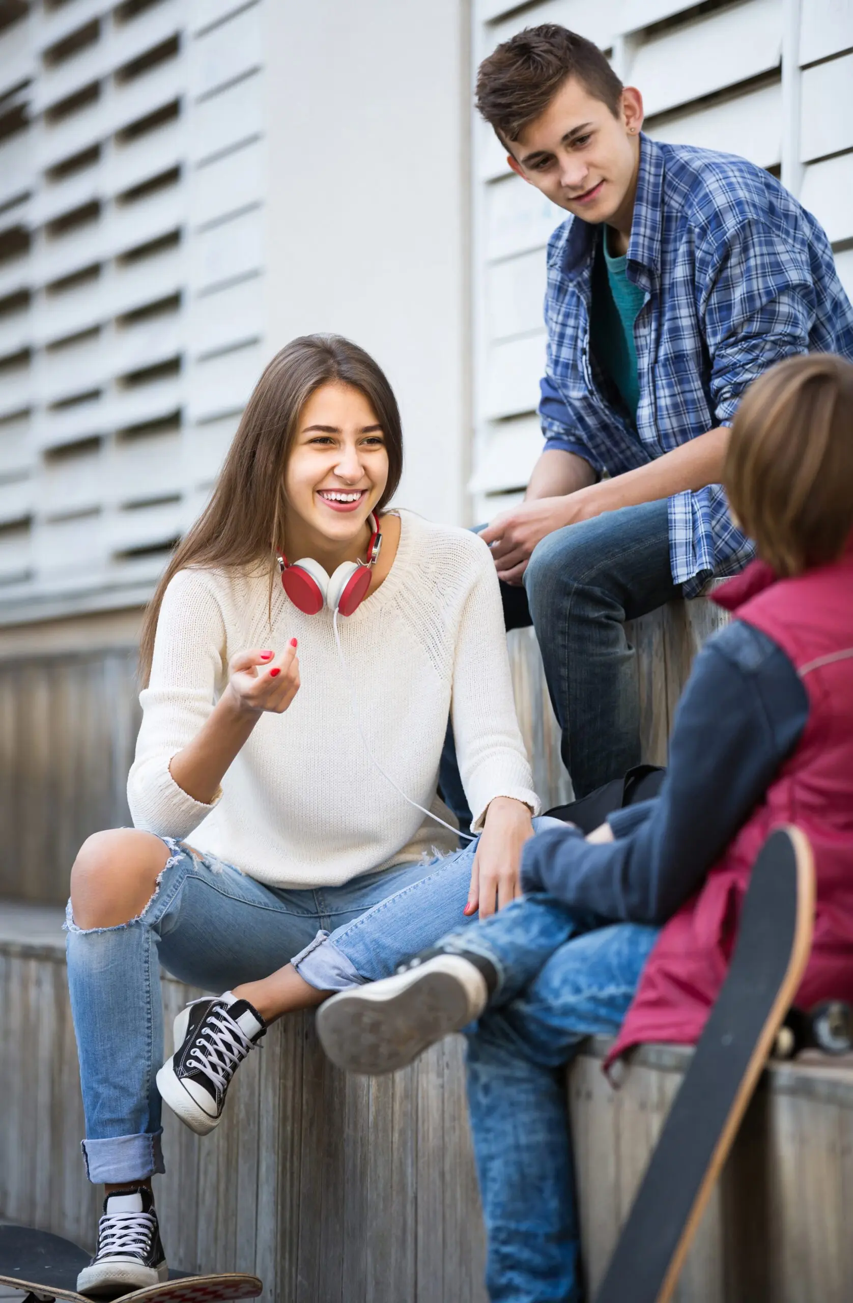 Three teens sitting on steps. One person is talking and gesturing with their hands.