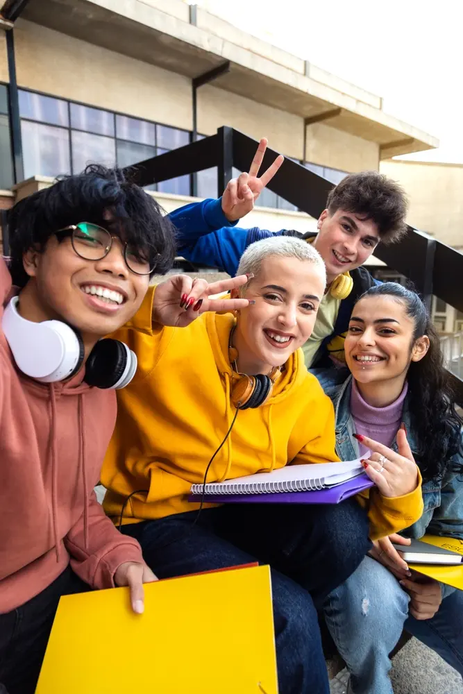 Group of four teens smiling and gesturing with their hands.