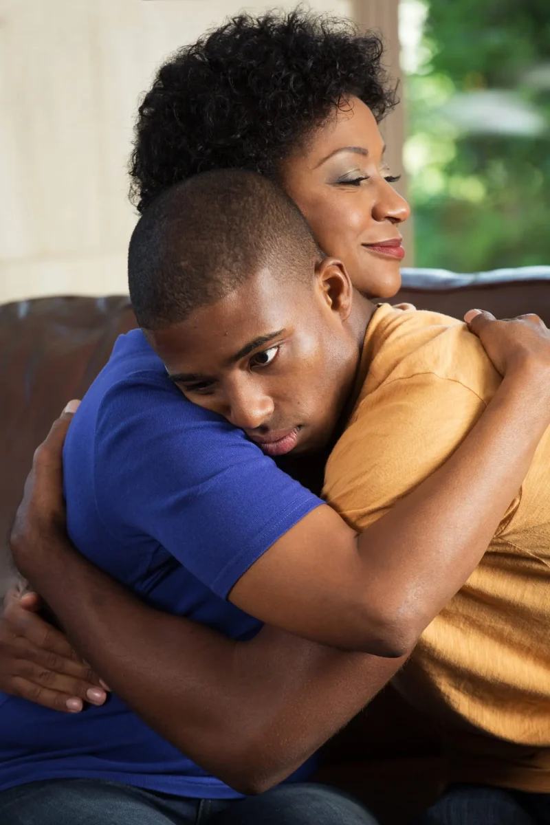 A mother and a son embracing while seated.