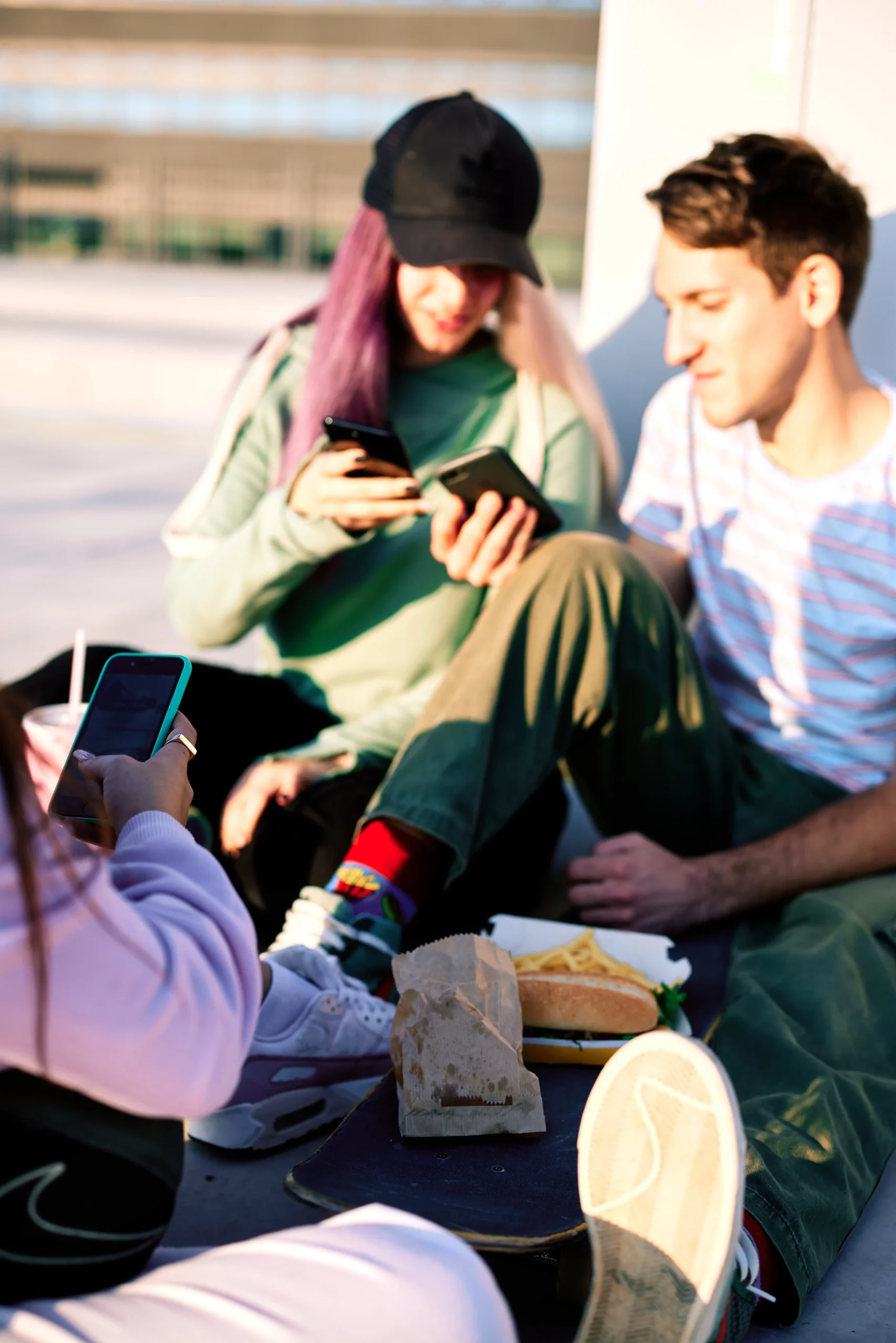 Two young people talking and looking at their phones.