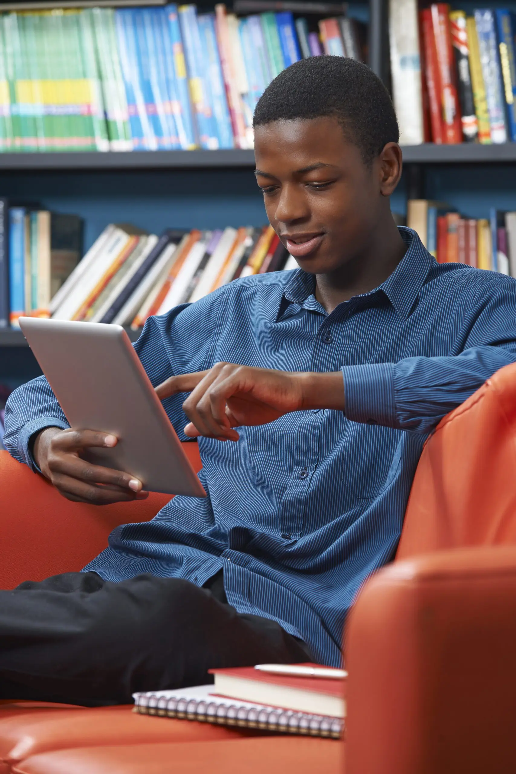 Young man sitting in a chair looking at a tablet.