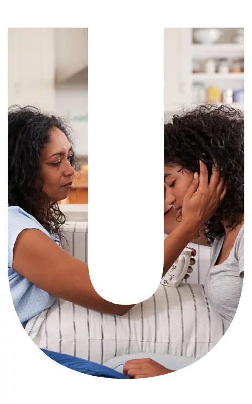 Image is in the shape of the letter "u" and features a mother consoling a daughter with her hand on her daughter's cheek.